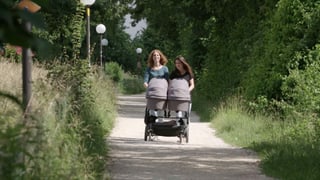 zwei Frauen stossen draussen einen Kinderwagen zwei Frauen stossen draussen einen Kinderwagen