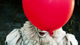 Ein Ballon verbirgt ein Clown-Gesicht.