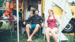 Zwei Menschen sitzen vor ihrem Camper