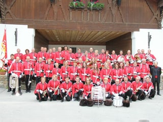 Die Musikantinnen und Musikanten in ihren roten Uniformen, sitzend und stehend, auf einem Gruppenbild.