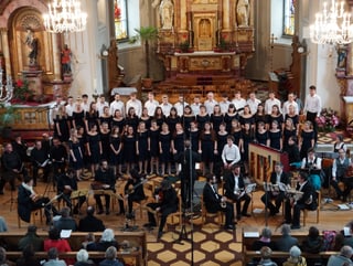 Einn Chor und verschiedene Musikerinnen und Musiker während eines Kirchenkonzerts.