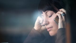 Frau am Telefon mit geschlossenen Augen. 