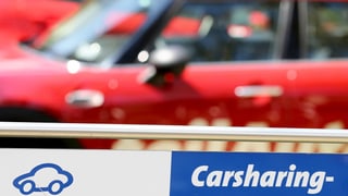 Carsharing-Schild vor einem roten Wagen.