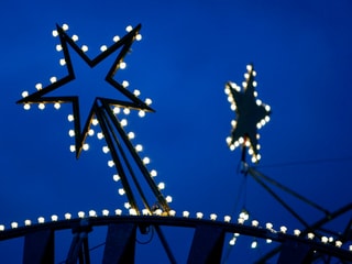 Weihnachtsbeleuchtung in Form von zwei Sternen vor blauem Himmel. 