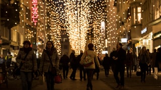 Menschen in einer Strasse mit Weihnachtsbeleuchtung.