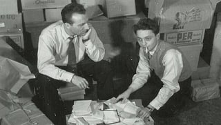 Die Glückskette-Gründer Roger Nordmann (links) und der Entertainer Jack Rollan knien 1946 vor einer Kiste mit Hilfsgütern