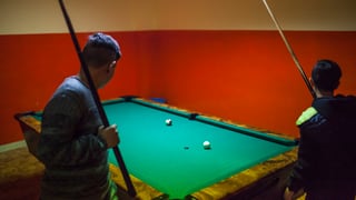 Zwei Kinder spielen Billiard.