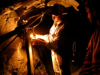 Minenarbeiter schaltet im Stollen Licht an.