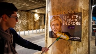 Wahlplakat von Marine Le Pen wird an einer Mauer angebracht.