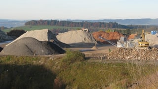 Sandhaufen mit Bagger auf einem Recyclingplatz.