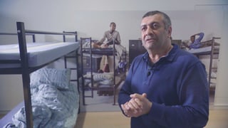 Mano Khalil steht in einem Flüchtlingszimmer mit Hochbetten. Mano Khalil steht in einem Flüchtlingszimmer mit Hochbetten.