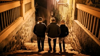 Drei Jungen gehen im Licht der Strassenlaterne eine Treppe hinunter.