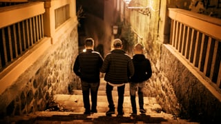 Drei Jungen gehen im Licht der Strassenlaterne eine Treppe hinunter. Drei Jungen gehen im Licht der Strassenlaterne eine Treppe hinunter.
