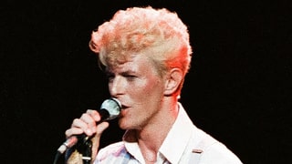 Ein Mann mit blondierten Haaren und einem Mikrophon in der Hand.