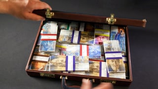 Ein Koffer gefüllt mit Schweizer Banknoten ist zu sehen.