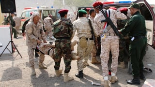 Soldaten tragen verwundeten Kollegen in Rettungswagen.