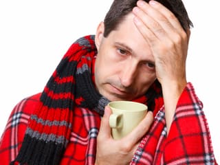 Ein Mann mit Grippe und einer Tasse Tee. 