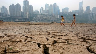 Kinder vor chinesischer Stadt auf vertrocknetem Boden.