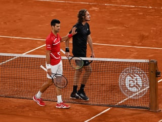Novak Djokovic und Stefanos Tsitsipas begegnen sich am Netz.