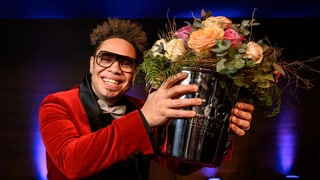 Mann in rotem Jackett mit Blumenstrauss in der linken Hand