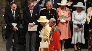 Elton John und weitere Eingeladene stehen bei einem Auftritt der Queen und Prinz Philip Spalier.