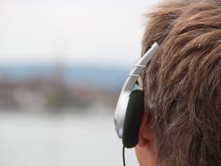 Reto Scherrer mit Kopfhörer blickt in die verschwommene Ferne.