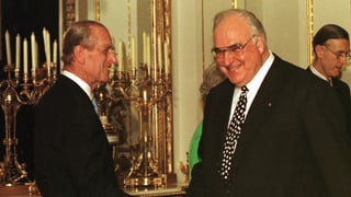 Prinz Philip schüttelt Bundeskanzler Helmut Kohl die Hand. Beide Männer in den schwarzen Anzügen lachen.