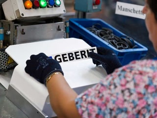 Frau klebt Geberit-Schild auf
