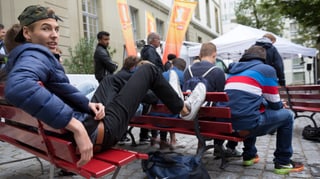 Jugendliche sitzen auf Bänken.