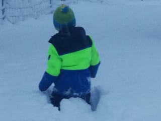 Junge in Skikleidern im tiefen Schnee