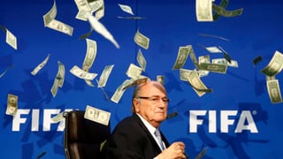 Blatter vor dem Fifa-Schriftzug (weiss auf blauem Grund), es regnet Dollar-Noten.