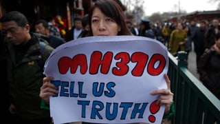 Eine Frau hält ein Transparent mit der Aufschrift «MH370, tell us truth!»