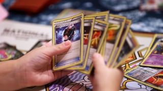 Hände, die einen Stapel Pokémon-Karten wie einen Fächer auffalten. Hände, die einen Stapel Pokémon-Karten wie einen Fächer auffalten.