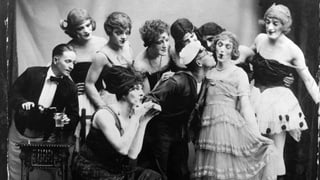 Cagney mit einer Gruppe von Männern, die als Frauen verkleidet sind. 