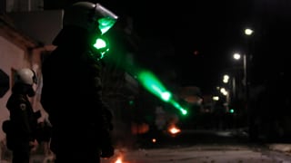 Ein Demonstrant blendet einen Polizisten in Kampfmontur mit einem Laserpointer.
