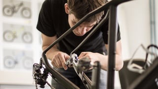 Ein Fahrradmechaniker montiert Teile an ein Mountainbike.