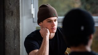 Junger Mann mit Wollmütze und nachdenklichem Gesicht. Das Gesicht auf die HAnd gestützt. Junger Mann mit Wollmütze und nachdenklichem Gesicht. Das Gesicht auf die HAnd gestützt.