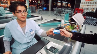 Eine Kundin überreicht einer Coop-Kassierin ihre Supercard