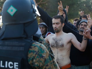 Ein Iraner hat sich an der griechisch-mazedonischen Grenze den Mund zugenäht. Weiter Männer stehen um ihn herum und protestieren leise. (reuters)