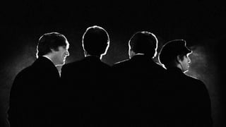 Die Beatles von hinten fotografiert, alles sehr dunkel.