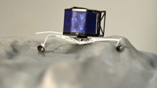 Ein Modell des Landegeräts Philae auf einem grauen Untergrund.