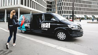 Frau läuft auf einen VW-Bus zu, dieser ist mit "Kollibri" beschriftet Frau läuft auf einen VW-Bus zu, dieser ist mit "Kollibri" beschriftet