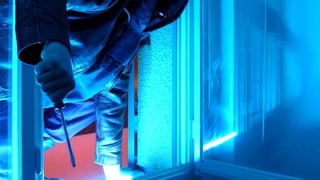 Ein einbrecher steigt in ein Fenster ein.
