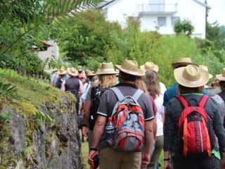 Blick von hinten auf die Wandergruppe, die zwischen ein paare Häusern durchmarschiert.
