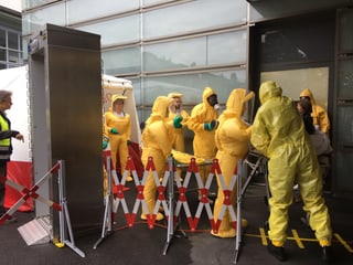 Mitarbeiter in gelben Schutzanzügen.