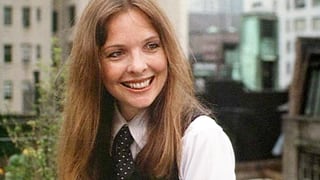 Frau lächelt auf einem Balkon in Manhattan und trägt eine Krawatte.