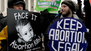 Zwei Demonstranten mit Schildern – eines pro Abtreibung, eines dagegen.