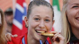 Judith Wyder beisst auf ihre WM-Goldmedaille, die um ihren Hals hängt.