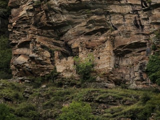 Heidenhaus von Dongio unterhalb einer Felswand