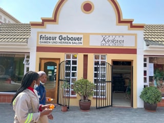 An einem Gebäude steht auf Deutsch Friseur, zwei Frauen gehen daran vorbei.